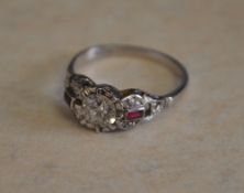 A platinum brilliant cut central diamond ring with ruby and diamond chip ornate shoulders,