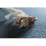 A platinum brilliant cut central diamond ring with ruby and diamond chip ornate shoulders,