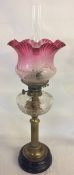 Victorian paraffin lamp on a brass column with a cranberry glass shade