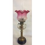 Victorian paraffin lamp on a brass column with a cranberry glass shade