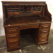 An early 20th century oak tambour front desk on twin pedestals