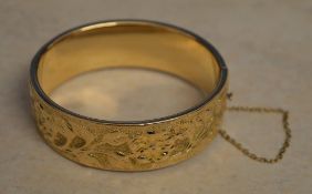 An ornately decorated 9ct gold bangle with safety chain, total approx weight 31.