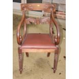 A Regency mahogany carver chair with shoulder board and back rail carved foliate scrolls, scroll