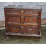 A 17th Century oak chest of two short and two long drawers with panelled fronts and later brass