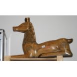 A carved wooden model of a recumbent deer, 29" long (lacks antlers)