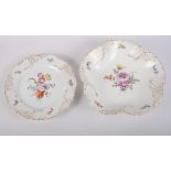 A continental porcelain part dessert service with gilt decorated borders and floral painted centres,
