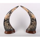 A pair of buffalo horns with engraved design of dragons and tigers, on wooden bases