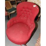 A Victorian nursing chair, upholstered in a red fabric, on turned supports