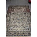 A Persian rug decorated stylised foliage and cypress trees on an ivory ground with three border