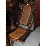 A Victorian carved walnut folding low seat chair with cane panels