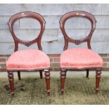 A set of four Victorian mahogany balloon back dining chairs with stuffed over seats, on turned