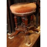 A Victorian mahogany revolving top piano stool, on four turned columns and splayed supports