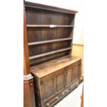 An oak dresser, the upper section with plate shelves over cupboards and two shallow drawers, on