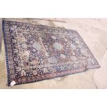 A Persian rug decorated scrolling foliage and bushes, etc, on a navy blue ground, 85" x 56"