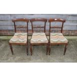 A set of three William IV mahogany carved bar back dining chairs with drop-in seats, on reeded