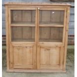 A 19th Century waxed pine side cupboard enclosed two glazed panel doors, on block base, 38" wide