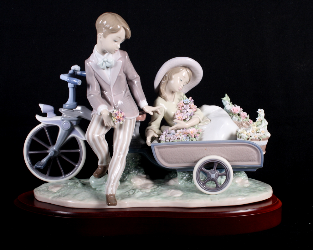 A Lladro china group of a boy and girl with bicycle and cart, 16" long, in original box