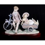 A Lladro china group of a boy and girl with bicycle and cart, 16" long, in original box