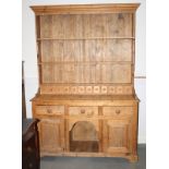A waxed pine dresser, the upper section with plate shelves and spice drawers over three drawers,