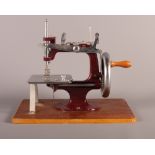 A miniature travelling sewing machine on a wooden base