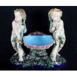 A Minton majolica centrepiece formed as two putti carrying a shell, 11 1/2" high (restored)