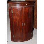 A late Georgian mahogany bowfront corner cupboard enclosed two doors, 24" wide