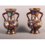 A pair of Japanese cloisonne two-handled vases with floral mons on a black ground, 9" high
