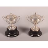 Two Art Nouveau embossed silver two-handled trophies and covers, 5.3oz troy approx, on ebonised