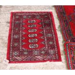 A Bokhara design rug decorated six flattened guls on a red ground, 34" x 24" approx