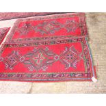 A Turkish rug of traditional design in red and blue with three blue and green medallions on a red