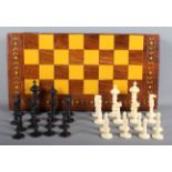 A 19th Century carved ebony and ivory chess set in later chessboard wooden box