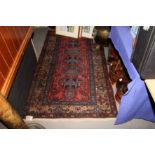 A Kurdish rug decorated five conjoined medallions on a red ground, 73" x 40" approx