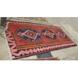 A kelim rug decorated three blue, orange and pink medallions, on a red ground, 132" x 62" approx