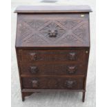 An early 20th Century oak bureau with flap and drawer fronts carved lion masks, 30" wide