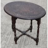 A late 19th Century dark stained oval occasional table with leaf carved central panel and carved