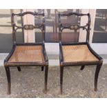 A pair of ebonised cane seat occasional chairs, on sabre front supports