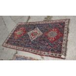 A Persian rug decorated three stepped medallions and stylised flowers on a blue ground with three