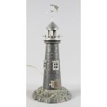 A cast metal table lamp modelled as a lighthouse on rocky base