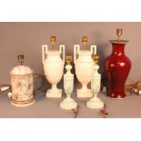 A pair of carved alabaster table lamps, two pottery table lamps and a pair of painted wooden lamps