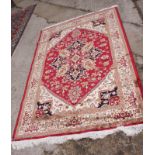 A Heriz design rug decorated central ivory medallion on a red ground with three border stripes,