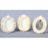 A group of three similar Chinese carved ivory oval photograph frames decorated dragons, 3" high