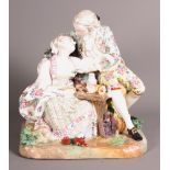 A 19th Century German porcelain figure of 18th Century lovers seated at a table, 10" high