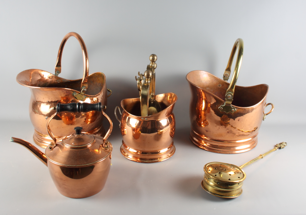 Two copper helmet coal scuttles, a copper kettle, a chestnut roaster and a fireside companion set