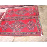 A Turkish rug of traditional design in red and blue with three blue and green medallions on a red