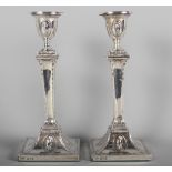A pair of silver candlesticks with classical decoration, on square bases, 9" high