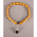 A Modernist silver necklace set single smoky quartz and an amber coloured bead necklace