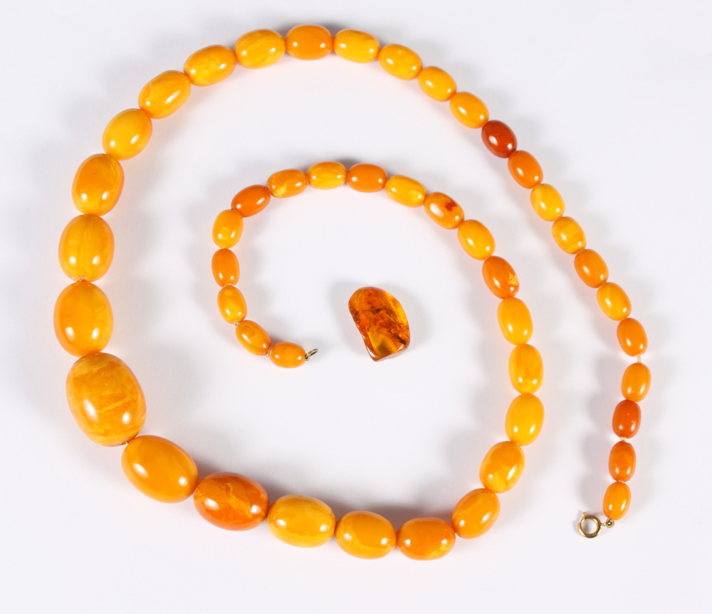 A graduated "egg yolk" amber bead necklace, 31" long, the largest bead 1 1/4" wide, 87.6g