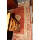 A Nepalese rug decorated central ivory medallion on a rust ground with border, 72" x 48" approx