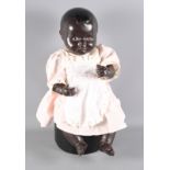 An early 20th Century dark brown doll with articulated composition body and later clothing, 17"