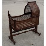 A 19th Century mahogany framed cradle with caned sides and hood, on mahogany stand